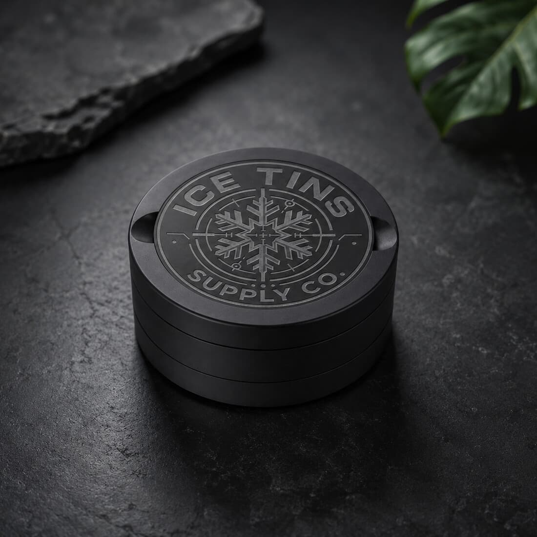 The Ice Tin on a dark stone surface, matte black Cerakote finish